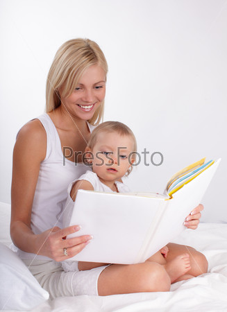 Mother reading book to a daughter at home