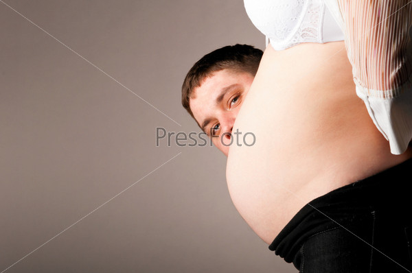 man is watching from behind the stomach of his pregnant wife