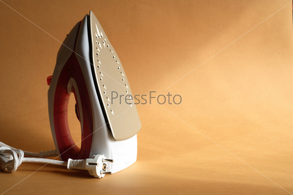Modern electric iron standing on nice gold background with sun lighting