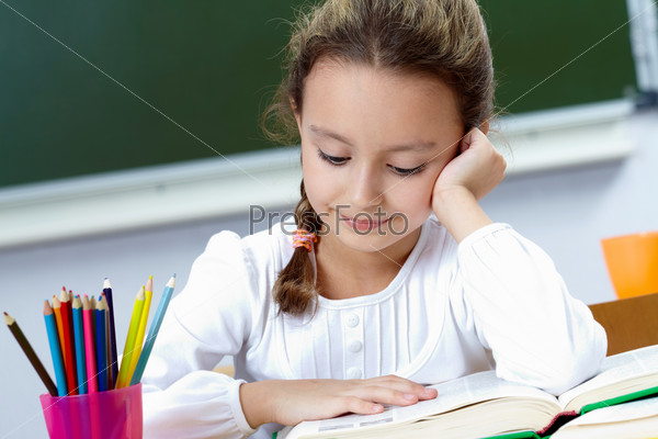 Portrait of pretty girl reading at workplace, stock photo