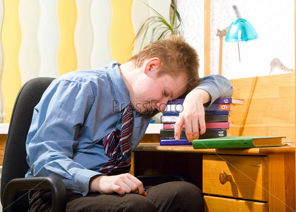 Schoolboy fell asleep, being tired of doing lessons, stock photo
