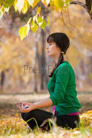 beautiful girl with dark hair, yoga in the yellow autumn\
leaves