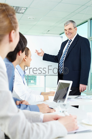 Senior business man showing something on a whiteboard to his colleagues