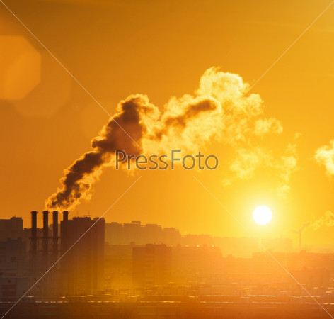 Industrial factory smoke from smokestacks over sunset sky