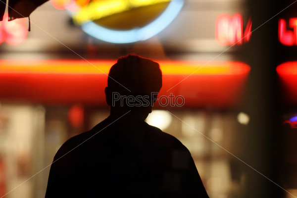 Black male silhouette over blurred neon lights background in night city