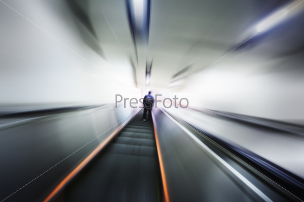 Lonely person moving up on escalator stairway. Blurred motion perspective.