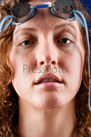 portrait of a woman swimmer looking at camera on blue background
