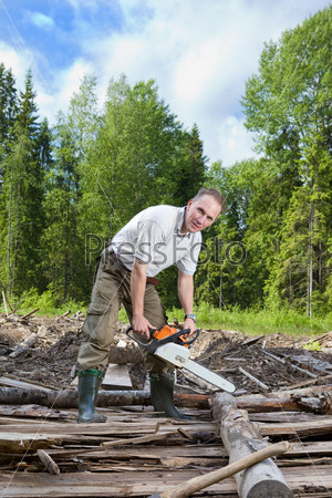 The man in wood saws a tree a chain saw