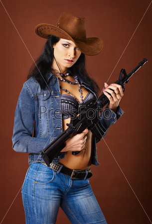 A beautiful young woman with a rifle on a brown background