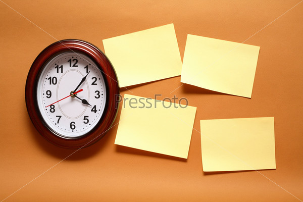 Few yellow blank adhesive notes hanging on the wall near clock