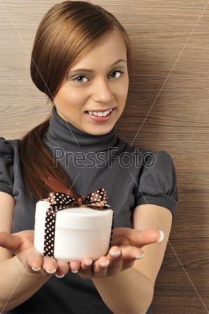 Portrait of a beautiful young woman offering a present. Office background.