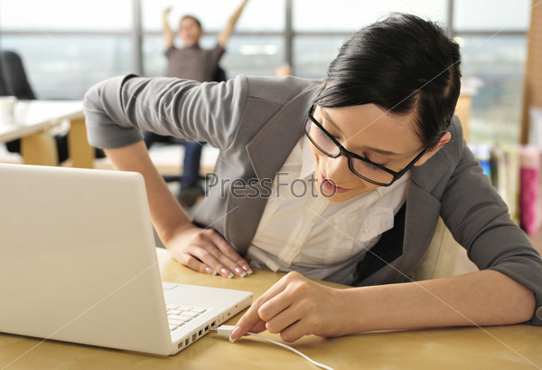 Closeup portrait of cute young business woman smiling at her workplace in an office environment. Connecting usb device to port on laptop