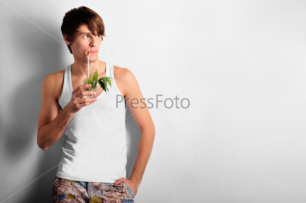 Closeup of young, handsome man thinking. Standing against wall and drinking cocktail. Ecology care concept