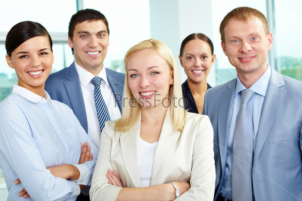 Portrait of friendly leader looking at camera with several employees behind