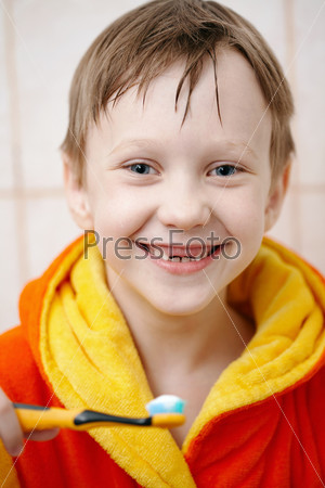 Boy in bathrobe hold of toothbrush and smiling/Brushing your teeth