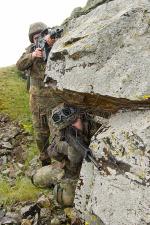 Couple of heavy equiped military men aiming the target