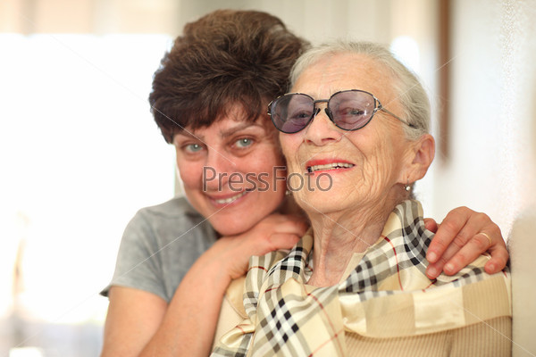 Happy woman with elderly mother, laughing together. Shallow\
DOF, focus on the senior woman.