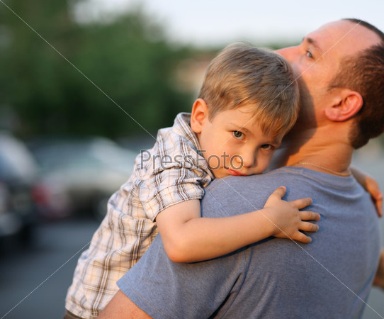 Little boy hugging hugging father around shoulders