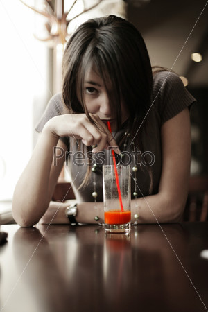 Brunette girl drinking red juice through straw. Shallow DOF.