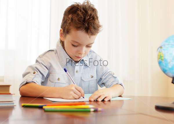 Маленький мальчик делает уроки дома