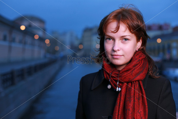 Portrait of a young redhead woman standing by a canal in St. Petersburg, Russia.