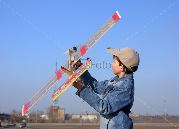 A boy starts the model of airplane in sky.