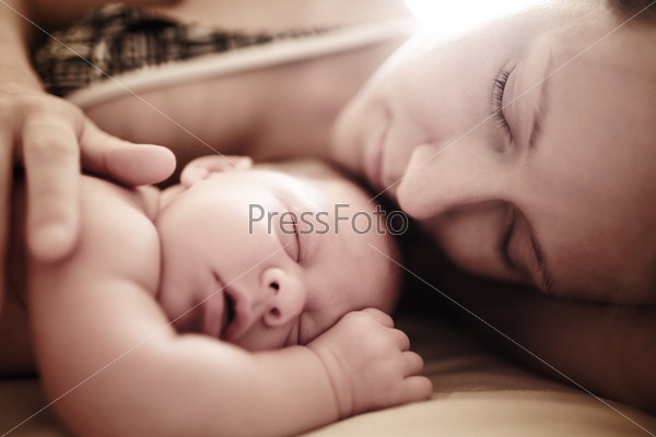 Newborn baby sleeping with mother. Shallow DOF.