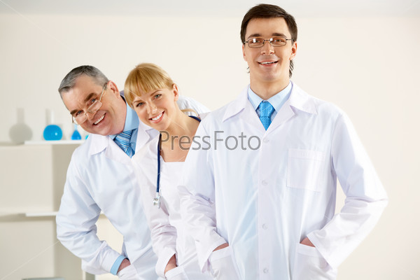Portrait of friendly therapists standing in line and looking at camera with happy clinician in front