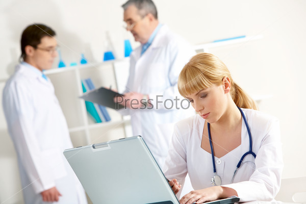 Photo of serious nurse with laptop planning work in working environment