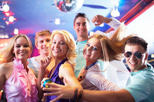 Portrait of glamorous girls dancing at party with happy friends near by