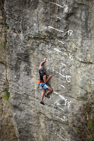 Rock climber battling his way up cliff