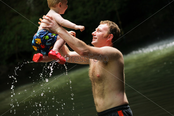 Father playing with son, raising him out of water.