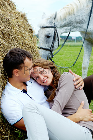Photo of affectionate couple having rest on haystack
