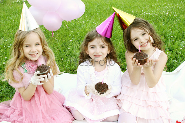 Three young girls outdoors merry, celebrate a birthday, give gifts