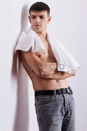 portrait of healthy handsome brunet guy posing with naked chest and towel on his neck