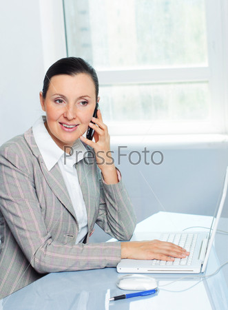 Attractive smiling young business woman using laptop