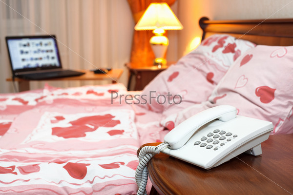 Bedroom interior with phone and laptop near bed on table