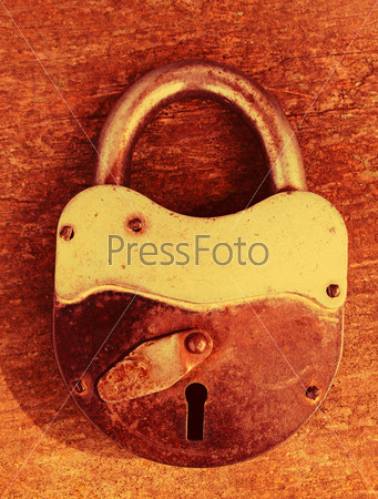 Old rusty padlock on wooden background, stock photo