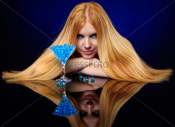 portrait of beautiful long-haired blue-eyed redhead girl with glass of fantasy cocktail  with gel balls