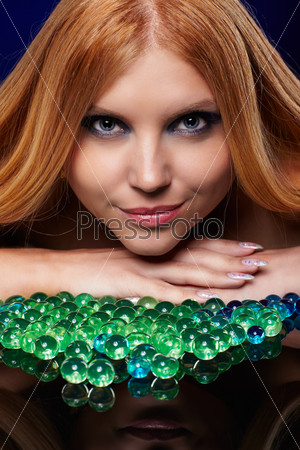 portrait of beautiful long-haired blue-eyed redhead girl posing with colorful gel balls