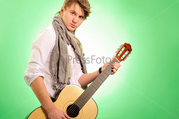 Closeup portrait of cute caucasian man playing the guitar over green background