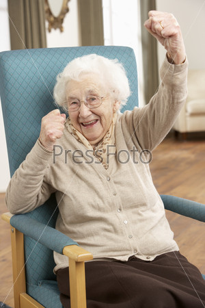 Радостная пожилая женщина сидит в кресле