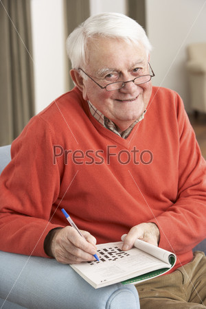 Stock Photo of Senior Man Relaxing In Chair At Home Completing Crossword