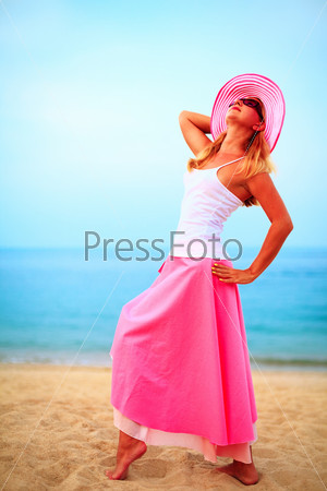 fashion woman posing near the ocean in pink clothes