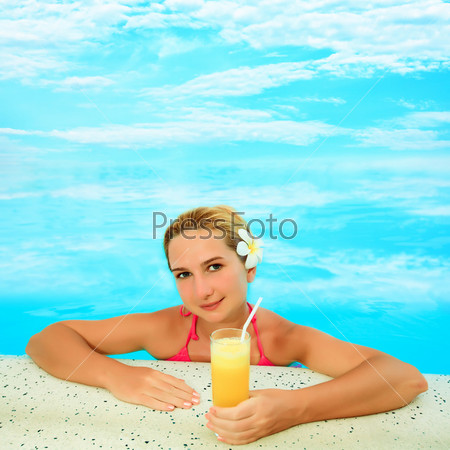 Young woman with juice in infinity pool