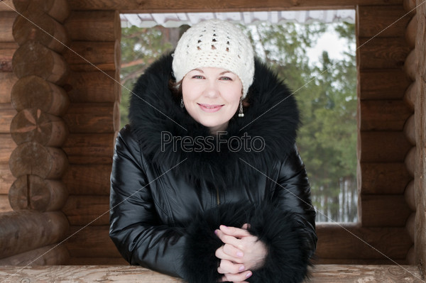 Young woman in winter clothes standing on house porch