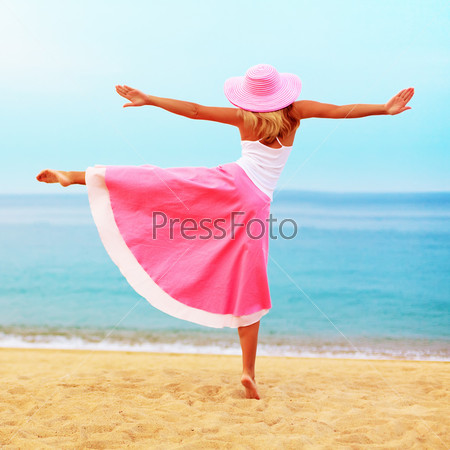 Woman dancing near the ocean in pink clothes