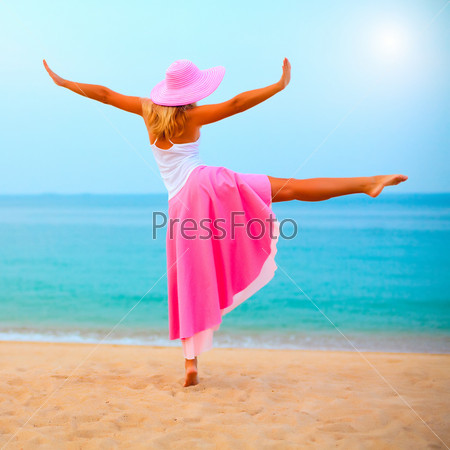 Woman dancing near the ocean in pink clothes