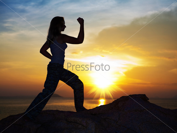 Silhouette of woman doing training exercise at sunrise time