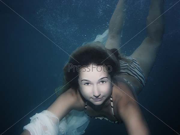 Young woman as a mermaid swimming underwater